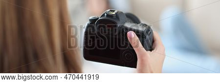 Woman Holds Professional Black Camera In Hands And Photographs Model At Home. Working Photographer A