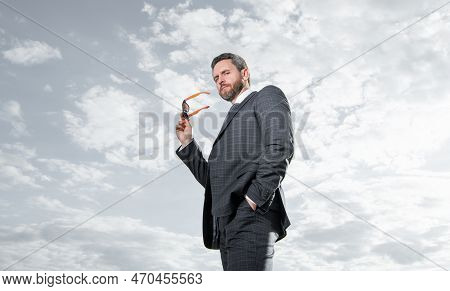 Businessman Bottom View. Businessman In Suit Holding Sunglasses. Grizzled Businessman Sky Background