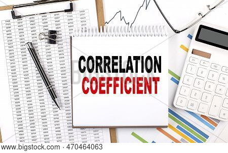 Correlation Coefficient Text On A Notebook With Chart, Calculator And Pen