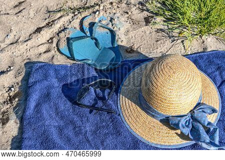 Straw Hat And Flip-flops On A Blue Towel On A Natural Beach Near The Tourist Resort Boltenhagen, Bal