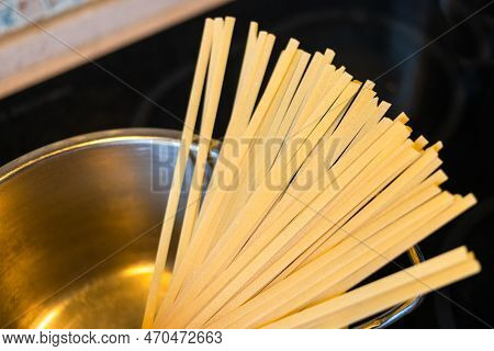 Portion Of Uncooked Linguine Pasta Closeup In Saucepan At Stove In Home Kitchen