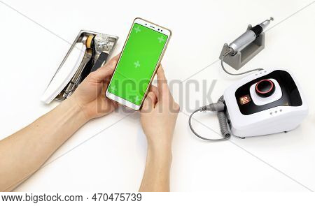 Nail Stylist Hands Hold Gadget With Green Chroma Key Screen, Sitting At Workstation In Nail Beauty T