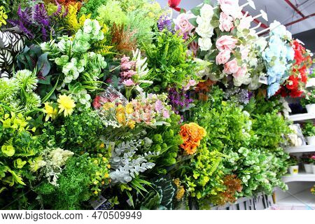 Artificial Flowers And Leaves Displayed On The Wall Of A Store For Sale. Bright Colored Flowers For 