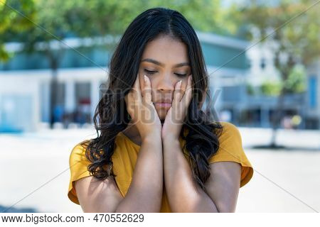 Sad And Depressed Mexican Young Adult Woman With Long Black Hair Outdoor In Summer In City
