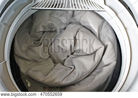 Roll Up The Duvet And Put It In The Washing Machine.for The Presentation Of The Washing Machine.