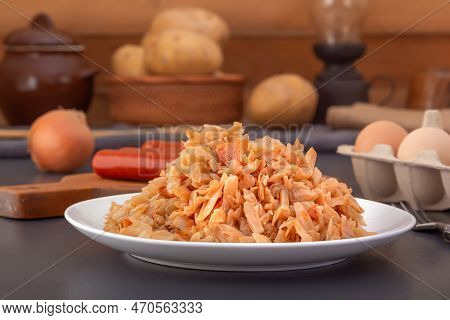 Stewed Cabbage - Bigos In A White Porcelain Plate Against The Background Of Smoked Sausages And Chic