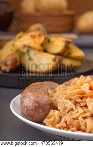 Braised Cabbage - Bigos And Grilled Sausage In A White Porcelain Plate Against The Background Of Rus