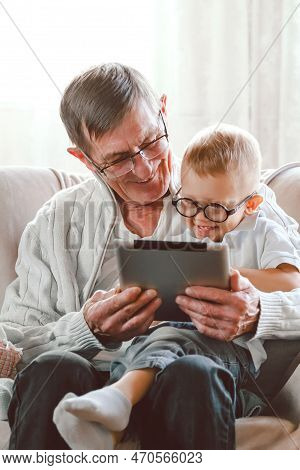 Elderly Grandfather And His Little Grandson Use A Tablet Device Together