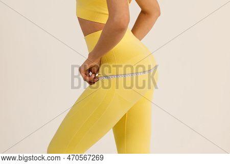 Sporty Woman In Yellow Sport Suit Measures Body With Measure Tape Isolated White Background.