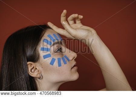 Kinesiotaping. A Girl With A Blue Kinesio Tape On Her Face. The Concept Of Facial Care