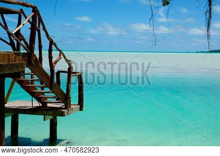 Steps Down To Over-water Wooden Landing On Tropical Island With View To Horizon Over Turquoise Water