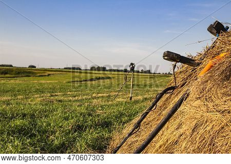 Metal Detector And Sapper Shovel On A Haystack In An Open Field Against The Blue Sky