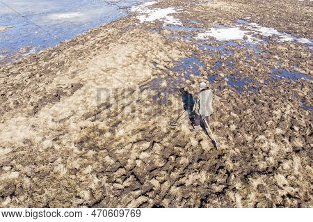 Man On A Treasure Hunt With A Metal Detector In The Woods On The Field, Photographed From A Drone, B