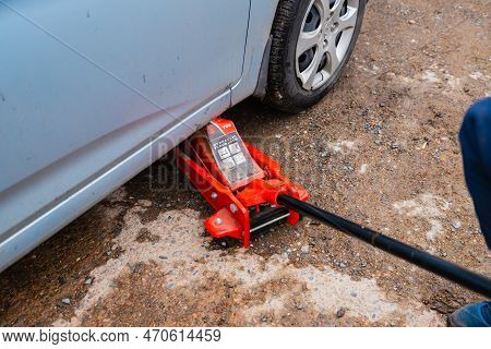 Man Jacked Up Blue Car With Red Jack Outside. Hyundai Car. Astana, Kazakhstan - 10.24.2022