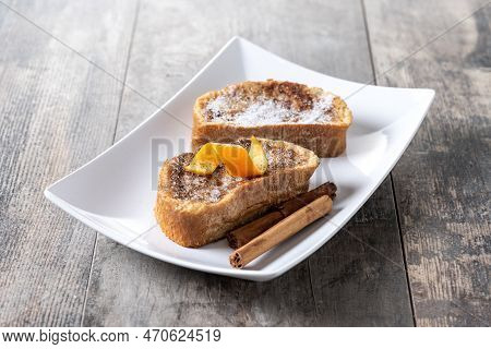 Traditional Homemade Spanish Torrijas Decorated With Cinnamon And Orange Peel On Wooden Table
