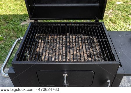 Cleaning A Dirty Grill While Standing On The Terrace And Emptying The Ashes.