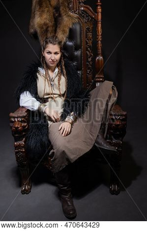 An Authoritative, Self-confident Woman In A Viking-style Fantasy Costume, Sitting On A High Chair Or