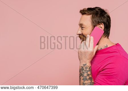 Side View Of Cheerful Man In Magenta T-shirt Calling On Mobile Phone Isolated On Pink.
