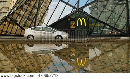 A Car Is Parked At A Mcdonald's Window. Close-up. In The Background, The Company Logo Is Reflected I