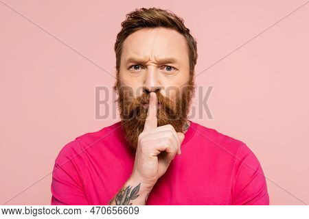 Frowning Bearded Man Showing Hush Sign And Looking At Camera Isolated On Pink.