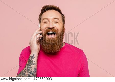 Joyful Bearded Man With Closed Eyes Talking On Mobile Phone And Laughing Isolated On Pink.