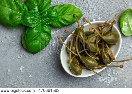 Capers. Marinated Or Pickled Canned Capers Fruit With Fresh Rosemary In A Small Bowl, On Gray Backgr