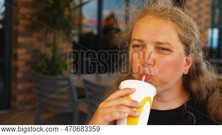 Young Woman Drinking Soda From A Paper Cup Through A Straw In Mcdonald's Fast Food Restaurant. A Tan