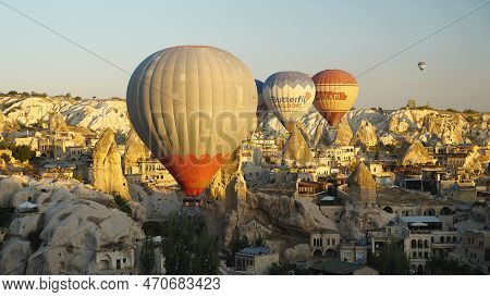 Colourful Balloons Fly Over The Mountainous Landscape Of Cappadocia, Turkey. A Popular Tourist Spot.
