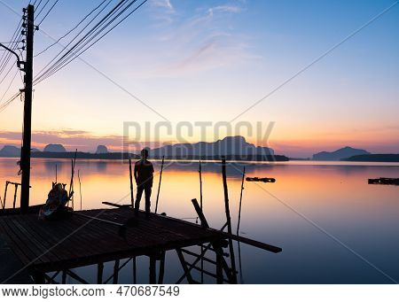 A Man Looking At Sunrise Sky At Fisherman Village, Sam Chong Tai, Phang-nga Province, Thailand.