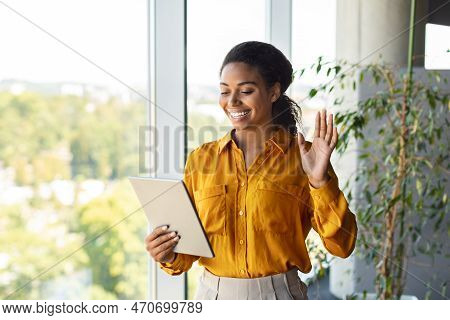 Happy African American Businesswoman Looking At Tablet And Waving Hand At Webcamera, Working In Offi