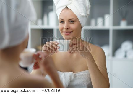 Young Woman Sits In The Bathroom In Front Of The Makeup Mirror And Does Cosmetic Procedures. Beautif