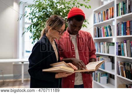 African American Student Shows Information Found In Exam Preparation Book To Project Partner Near Bo