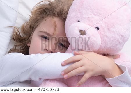 Child Wakes Up With Toy Teddy Bear From Sleep In Bed. Kid Wakes Up In The Morning In The Bedroom. Fa