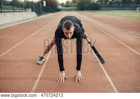 A Runner With Artificial Leg In Start Position At Stadium On Running Track.
