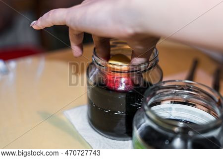 Young Woman Dyeing Easter Eggs At Home In The Kitchen In The Cucumber Glass And With Different Color