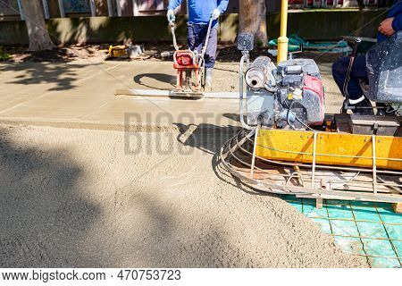Motor Of Self-leveling Power Trowel Machine Is Waiting. Behind Construction Worker Is Leveling Fresh