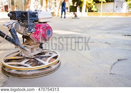 Worker Using Self-leveling Power Trowel Machine With Gas Engine Has Wheels With Pads, Plate And He I