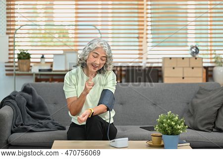 Satisfied Senior Woman Measuring Blood Pressure With Digital Pressure Gauge At Home. Elderly Healthc