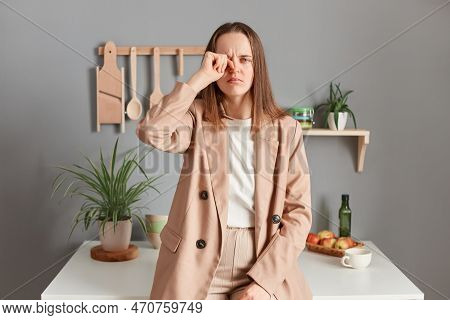 Portrait Of Sleepy Tired Brown Haired Woman Wearing Beige Suit Standing Near Table On Kitchen At Hom