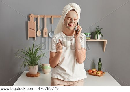 Pretty Woman With Cosmetic Mask On Face Drinking Morning Coffee And Talking Via Smartphone At Home I