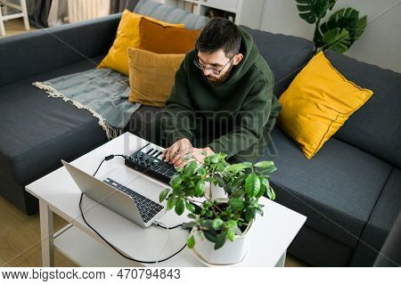 Man Music Producer Or Arranger Using Laptop And Midi Keyboard And Other Audio Equipment To Create Mu