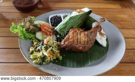 Crispy Black Fried Duck With Rice Covered In Banana Leaf, Some Veggetable And Special Mash Chili.