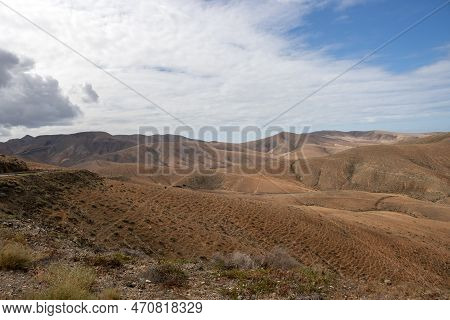 Shapes And Lines Of The Mountains Of The Volcanic Origin. Light Brown Color Of The Soil. Sky With Cl