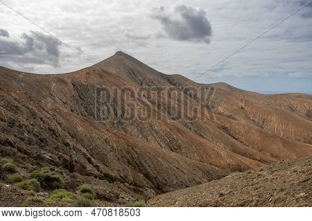 Shapes And Lines Of The Mountains Of The Volcanic Origin. Light Brown Color Of The Soil. Sky With Cl