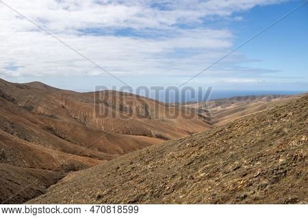 Shapes And Lines Of The Mountains Of The Volcanic Origin. Light Brown Color Of The Soil. Sky With Cl