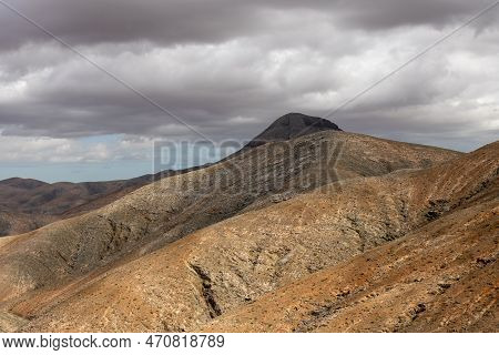 Shapes And Lines Of The Mountains Of The Volcanic Origin. Light Brown Color Of The Soil. Sky With Cl