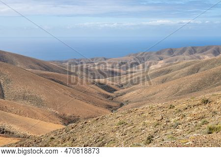 Shapes And Lines Of The Mountains Of The Volcanic Origin. Light Brown Color Of The Soil. Sky With Cl