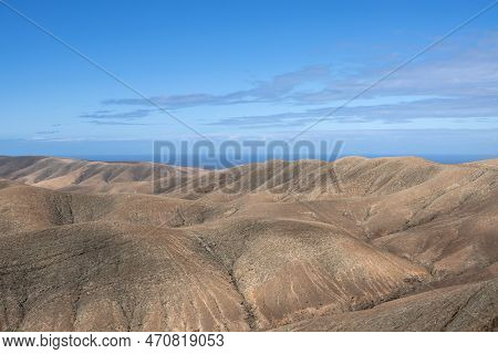 Shapes And Lines Of The Mountains Of The Volcanic Origin. Light Brown Color Of The Soil. Sky With Cl