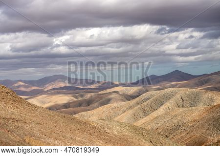 Shapes And Lines Of The Mountains Of The Volcanic Origin. Light Brown Color Of The Soil. Sky With Cl