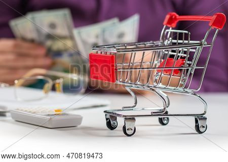 Man Calculates The Budget. Shopping Cart A On Table With Calculator And Paper And Mohey In Hadns. Bu